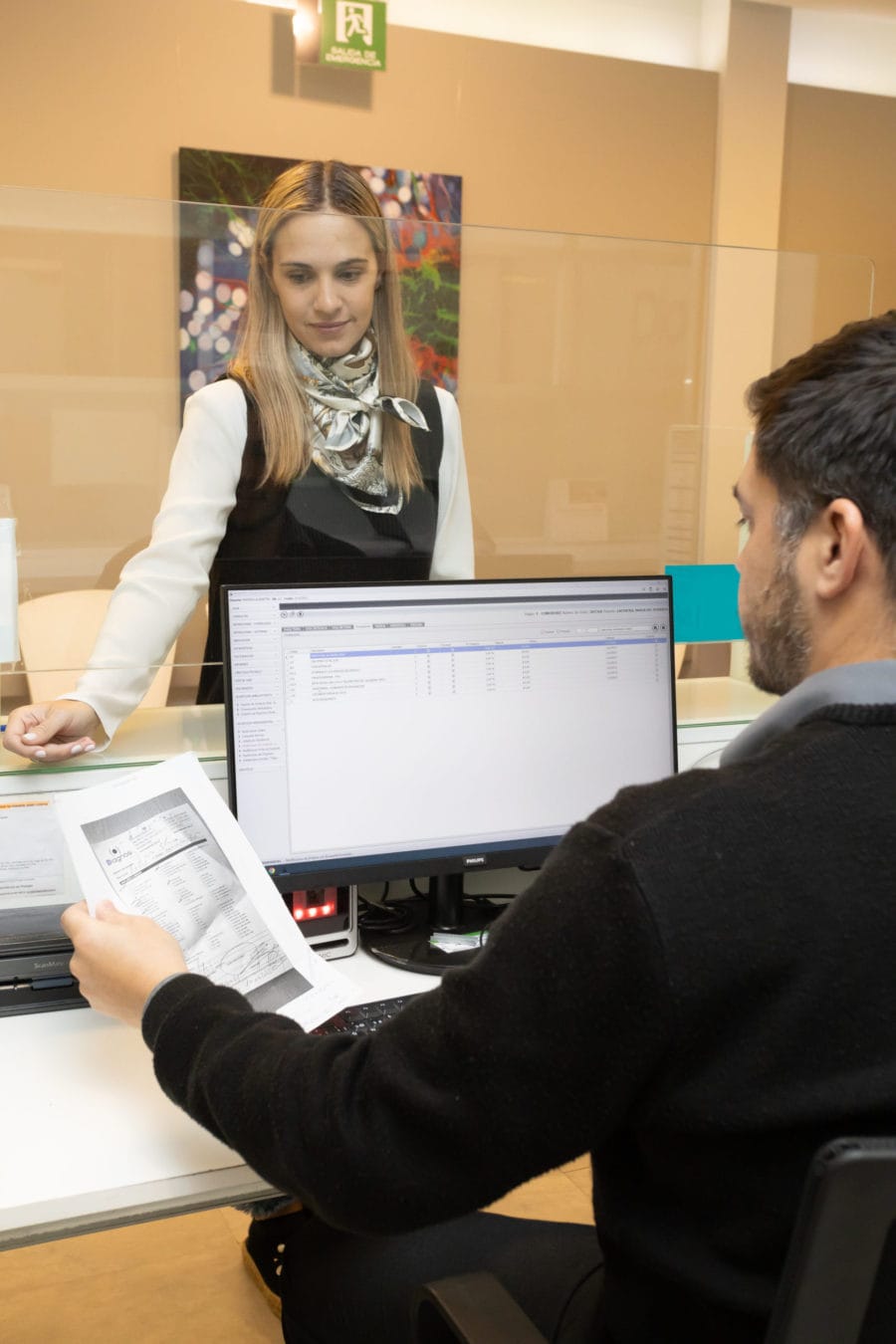 Personal de laboratorio atendiendo a un paciente en recepción, brindando información y asistencia con amabilidad.